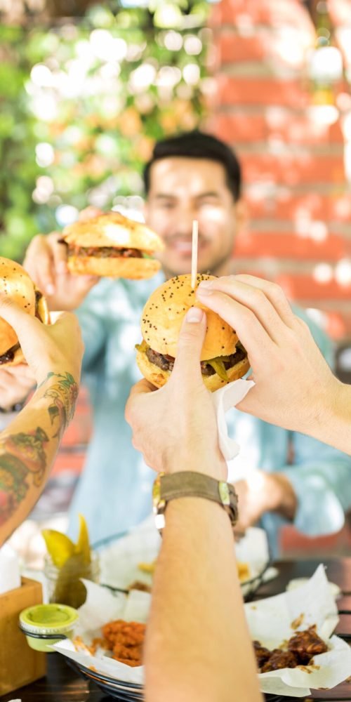 friends showing excitement by toasting burgers